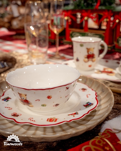 Table de Noël avec vaisselle festive décorée d'ours et de cadeaux.